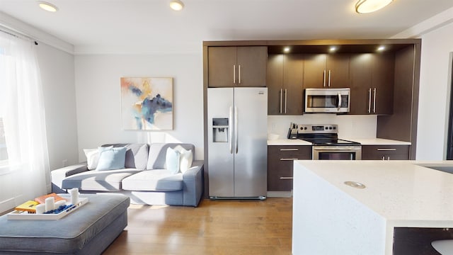 kitchen with stainless steel appliances, dark brown cabinetry, and light hardwood / wood-style floors