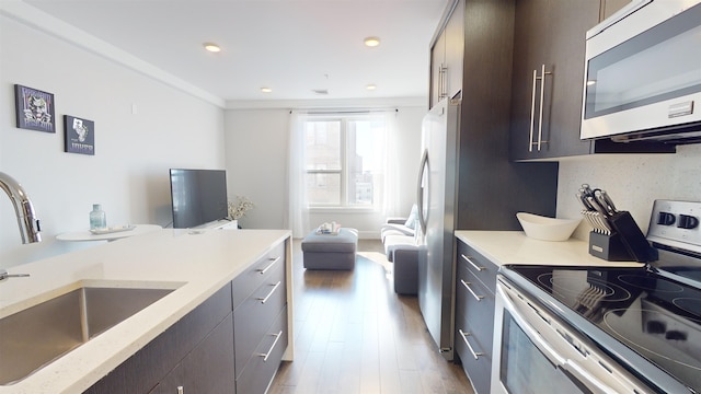 kitchen with tasteful backsplash, sink, dark brown cabinets, and appliances with stainless steel finishes