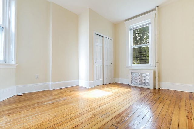 spare room with light wood-style floors, radiator, and baseboards