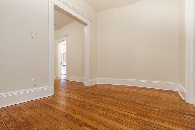 spare room with wood-type flooring and baseboards