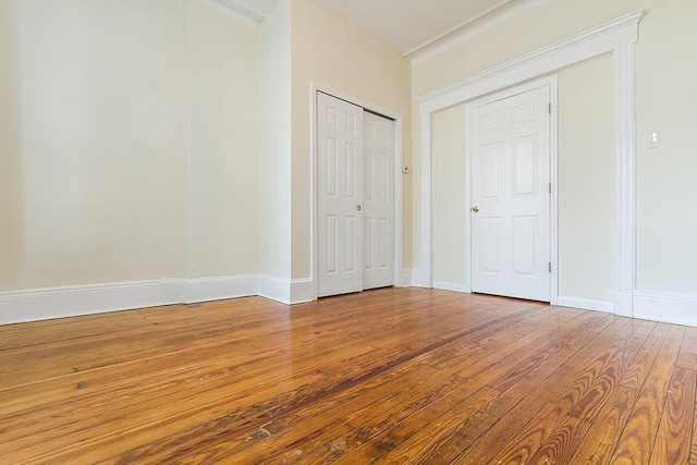 unfurnished bedroom featuring a closet, hardwood / wood-style flooring, and baseboards