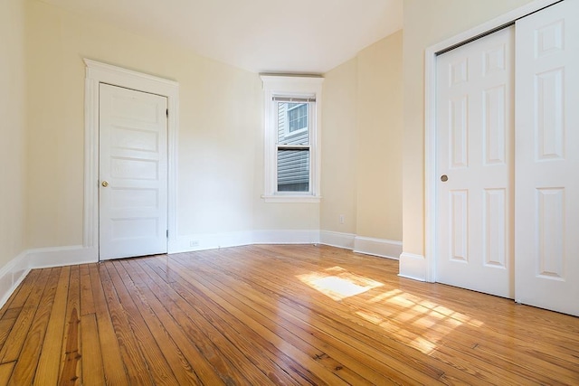 unfurnished bedroom featuring baseboards, a closet, and light wood-style floors