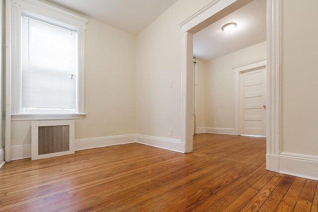 unfurnished room featuring radiator heating unit, baseboards, and wood-type flooring