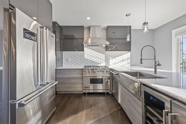 kitchen with high quality appliances, wall chimney range hood, hanging light fixtures, wine cooler, and dark hardwood / wood-style floors