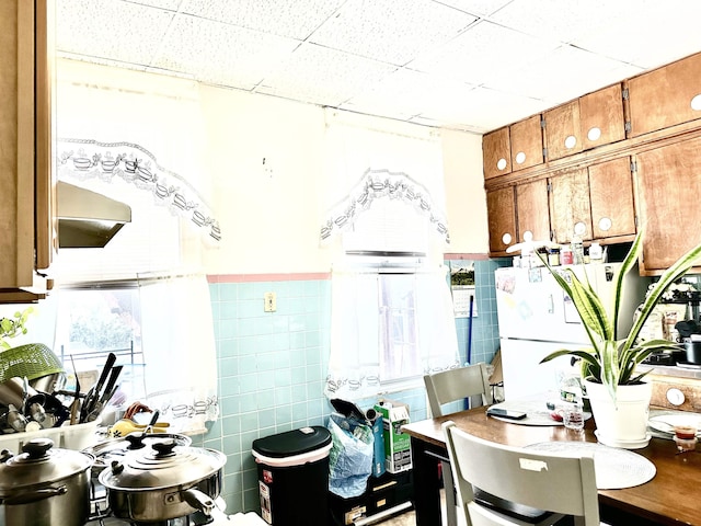 500 New York Ave, Jersey City, NJ 07087 - kitchen with brown cabinets, a paneled ceiling, a desk, range hood, and tile walls