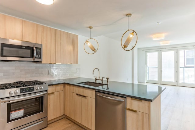 348 Baldwin Ave Unit 209, Jersey City, NJ 07306 - kitchen featuring appliances with stainless steel finishes, light brown cabinets, a peninsula, a sink, and decorative backsplash