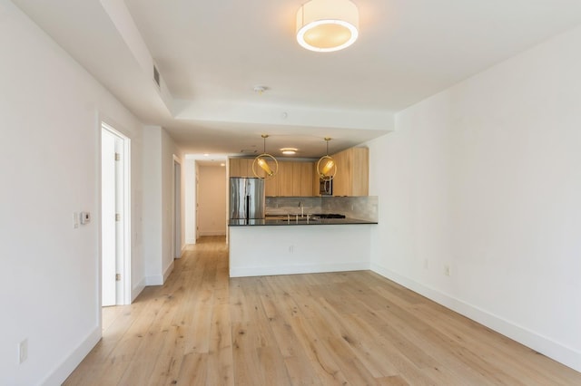 348 Baldwin Ave Unit 209, Jersey City, NJ 07306 - kitchen featuring appliances with stainless steel finishes, tasteful backsplash, dark countertops, a peninsula, and light wood-type flooring