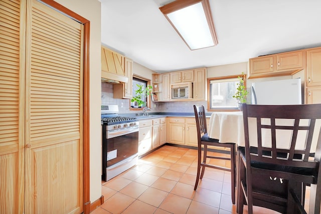 kitchen featuring light brown cabinetry, backsplash, white appliances, and a healthy amount of sunlight