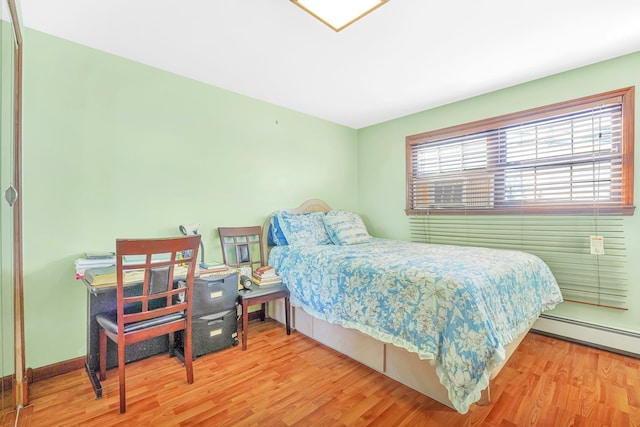 bedroom featuring a baseboard radiator, baseboards, and wood finished floors