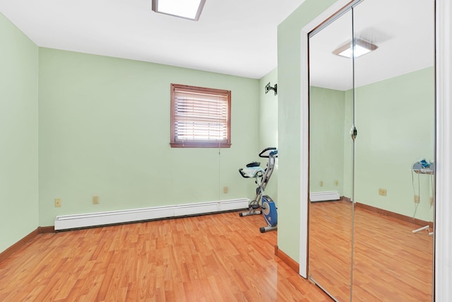 workout room with baseboards, light wood-type flooring, and baseboard heating