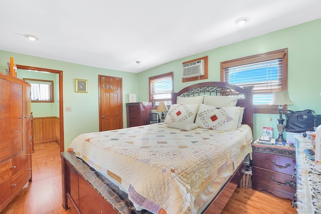 bedroom featuring a wainscoted wall, a wall unit AC, and light wood-type flooring