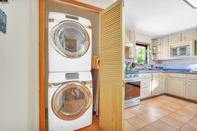 washroom with laundry area, light tile patterned floors, stacked washer and clothes dryer, and a sink