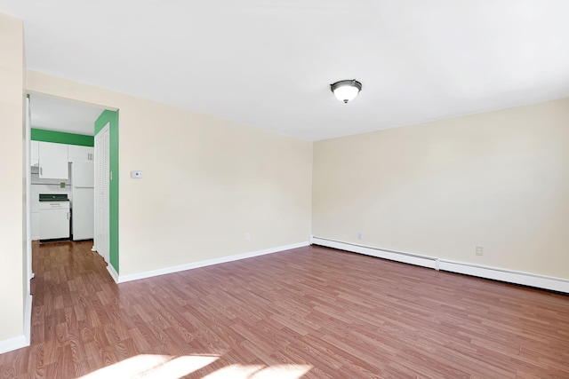 empty room with a baseboard heating unit, baseboards, and light wood finished floors