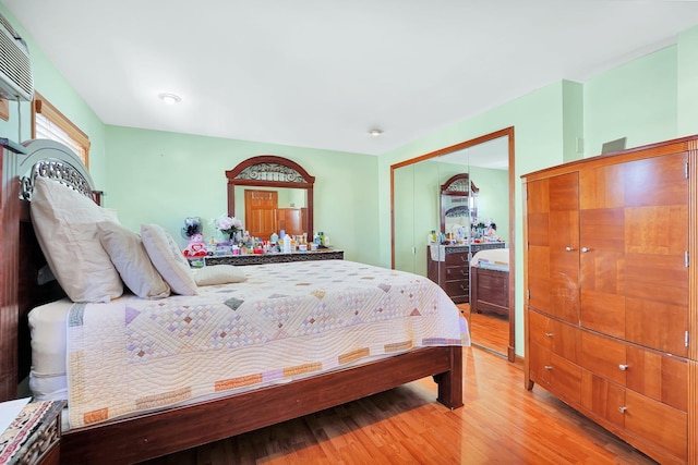 bedroom featuring a closet, a wall mounted air conditioner, and light wood-style floors