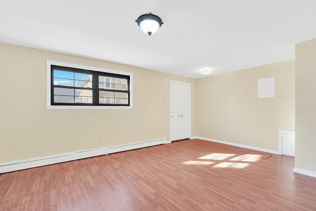 spare room featuring wood finished floors, baseboards, and baseboard heating