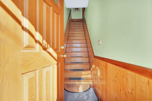 staircase featuring wood walls and wainscoting