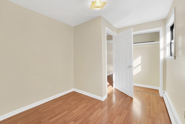 unfurnished bedroom with a baseboard radiator, baseboards, light wood-style floors, and a closet