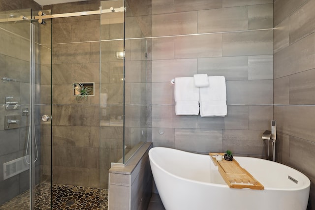 full bathroom featuring a stall shower, tile walls, and a freestanding tub