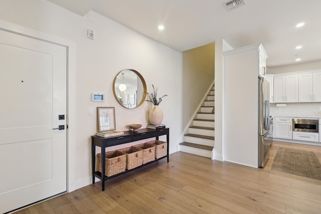 foyer entrance featuring visible vents, light wood-style flooring, recessed lighting, stairway, and baseboards