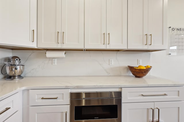 kitchen featuring white cabinetry, light stone countertops, and backsplash