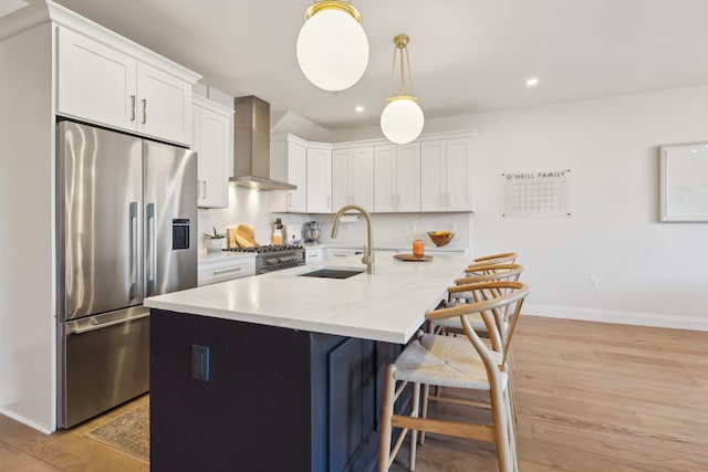 kitchen featuring a sink, wall chimney range hood, light wood-style flooring, and stainless steel appliances