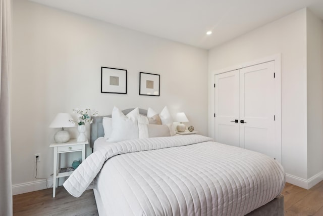 bedroom featuring light wood-style flooring, recessed lighting, baseboards, and a closet