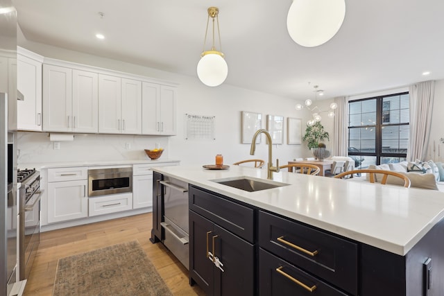 kitchen with dark cabinets, white cabinets, light countertops, and a sink