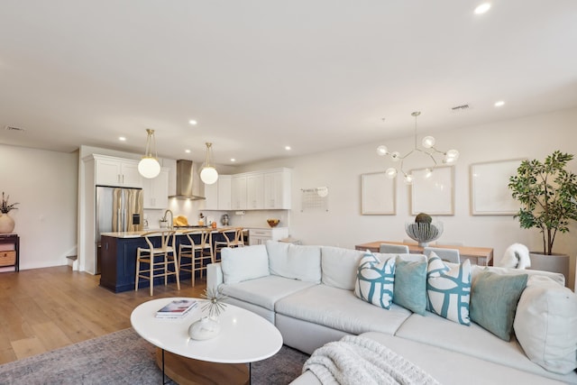 living area featuring an inviting chandelier, recessed lighting, light wood-style floors, and visible vents