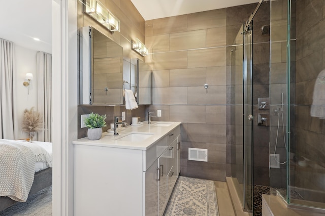 ensuite bathroom featuring a sink, visible vents, a stall shower, and double vanity