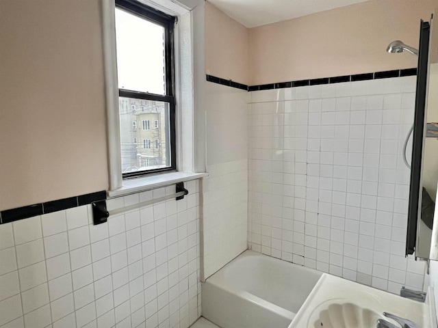 bathroom featuring tile walls and tiled shower / bath combo