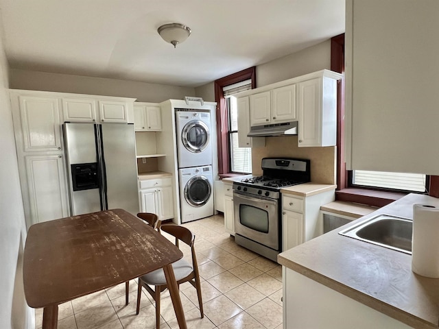 kitchen featuring white cabinetry, sink, stacked washer and clothes dryer, light tile patterned floors, and stainless steel appliances