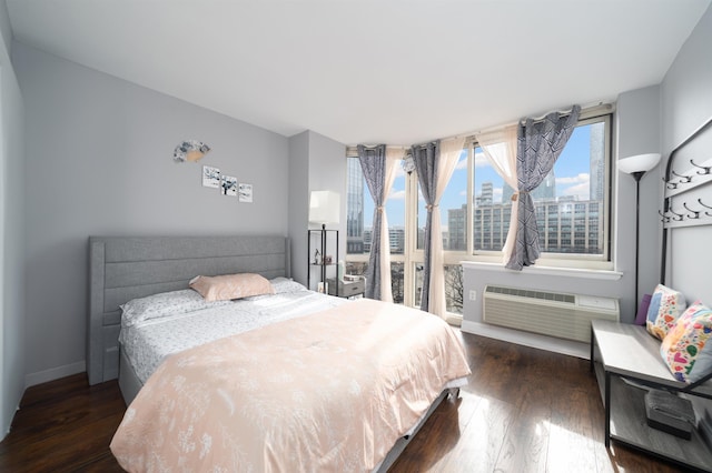 bedroom with a view of city, a wall mounted air conditioner, dark wood finished floors, and baseboards