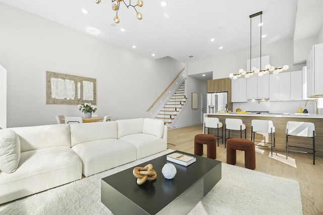 living room featuring a chandelier, stairway, recessed lighting, and light wood-style floors