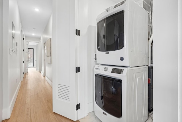 clothes washing area featuring stacked washer and dryer and light hardwood / wood-style floors