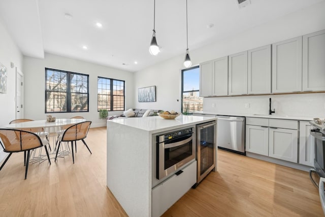 kitchen featuring sink, beverage cooler, hanging light fixtures, a center island, and stainless steel appliances