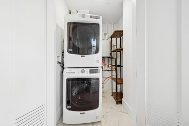 clothes washing area with water heater and stacked washer / dryer