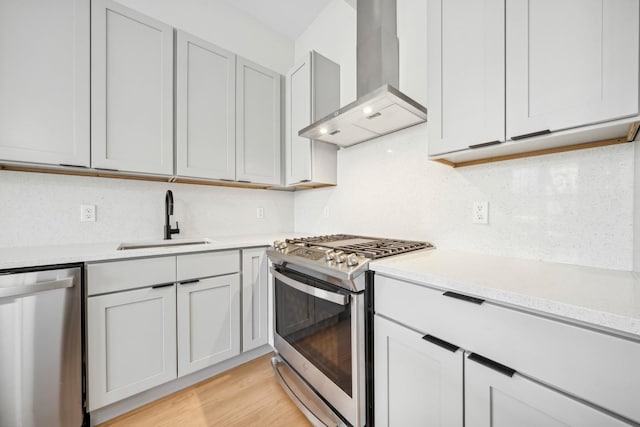 kitchen with appliances with stainless steel finishes, range hood, sink, backsplash, and light hardwood / wood-style flooring