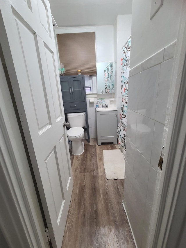 full bathroom featuring tile walls, toilet, vanity, and wood finished floors