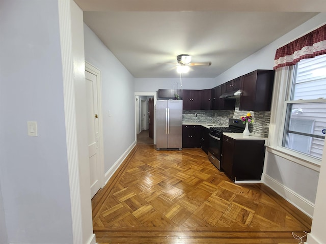 kitchen featuring range with gas stovetop, baseboards, freestanding refrigerator, decorative backsplash, and light countertops