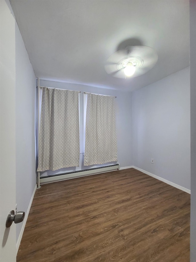 empty room featuring ceiling fan, baseboards, a baseboard heating unit, and dark wood-type flooring