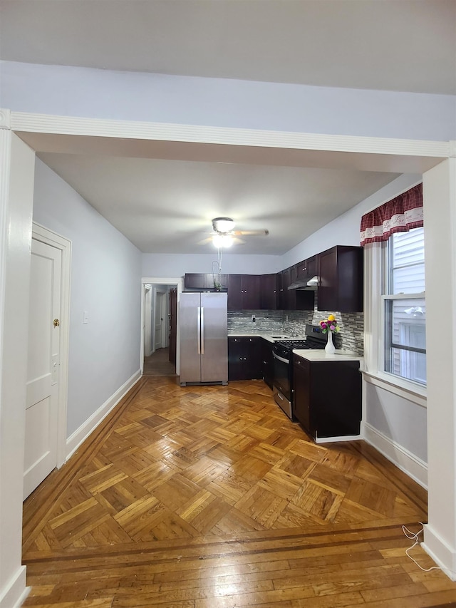 kitchen featuring under cabinet range hood, tasteful backsplash, stainless steel appliances, light countertops, and baseboards