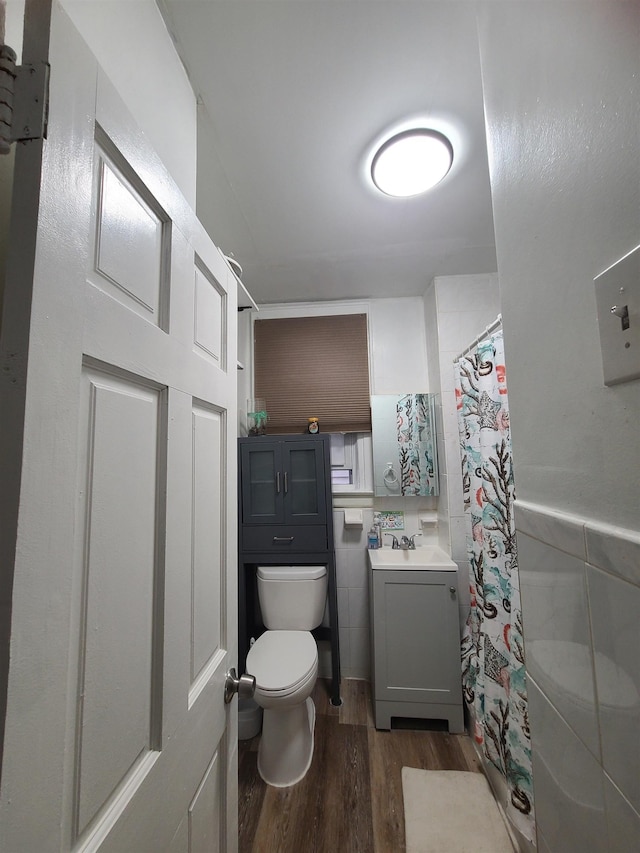 bathroom featuring tile walls, toilet, a shower with curtain, wood finished floors, and vanity