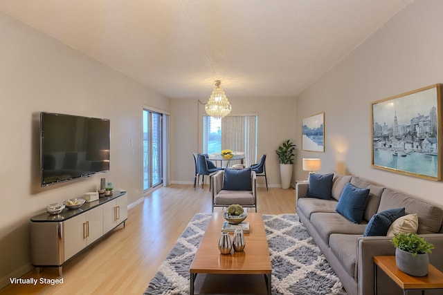 living area featuring a chandelier, light wood-style flooring, and baseboards