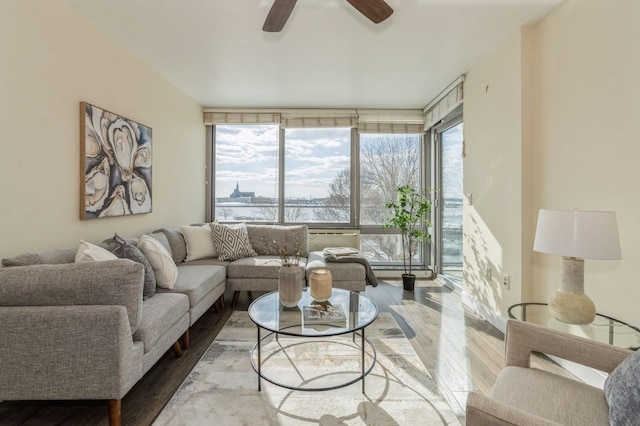 living room featuring ceiling fan, light hardwood / wood-style flooring, and a wall of windows