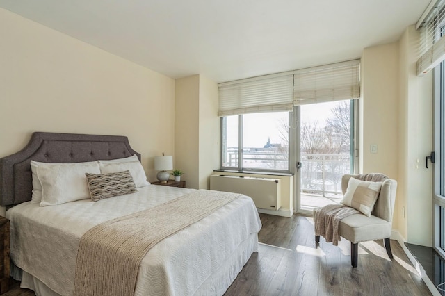 bedroom with access to outside, radiator heating unit, and dark hardwood / wood-style flooring