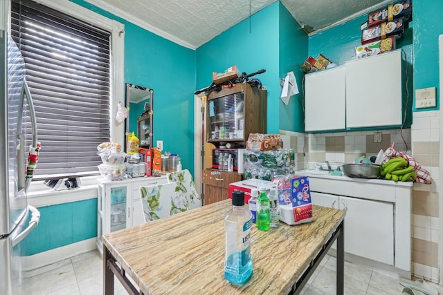 kitchen featuring white cabinetry, light countertops, and freestanding refrigerator