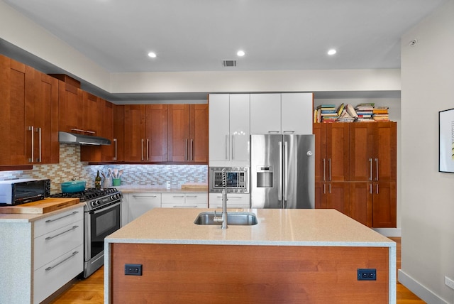 390 1st St Unit 3, Jersey City, NJ 07302 - kitchen with appliances with stainless steel finishes, under cabinet range hood, decorative backsplash, a kitchen island with sink, and light wood-type flooring