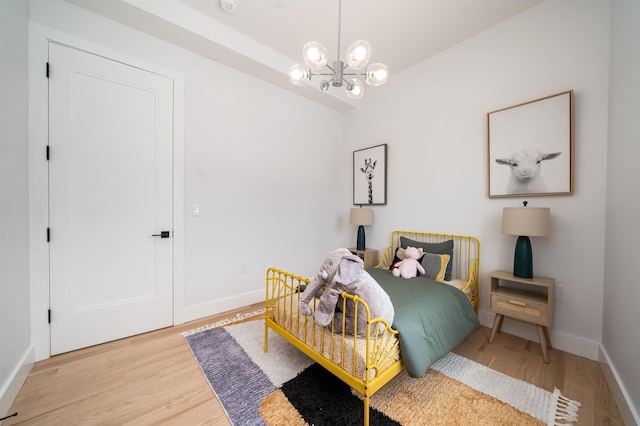 bedroom with hardwood / wood-style flooring and an inviting chandelier