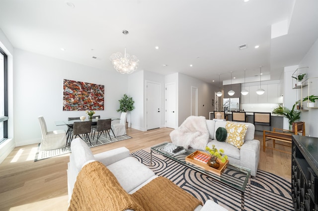 living room featuring a notable chandelier and light wood-type flooring