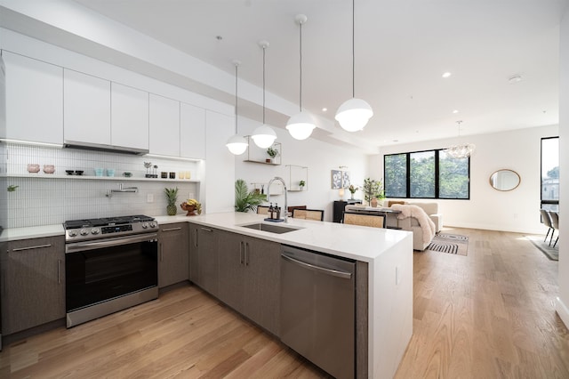 kitchen featuring sink, appliances with stainless steel finishes, hanging light fixtures, white cabinets, and kitchen peninsula